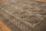 Angled view over the geometric guls and diamond border of a distressed vintage Ersari carpet.