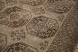 Detail of a distressed Ersari carpet's geometric guls and borders in oxidized silver and charcoal tones.