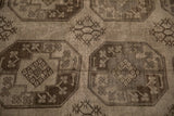Close view of the hand-knotted pile showing geometric guls with blossomed plants in charcoal tones.