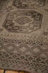Angled view of a distressed Ersari carpet's time-softened low pile and charcoal geometric patterns.