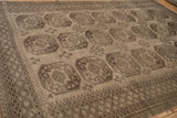 Low-pile texture and geometric gul pattern on a distressed vintage Ersari carpet in charcoal tones.