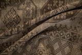 Soft folds on a vintage Ersari carpet show its low-pile texture and charcoal geometric motifs.