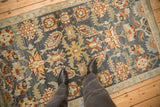 A lifestyle view of a distressed Malayer rug, showing its colorful floral pattern.