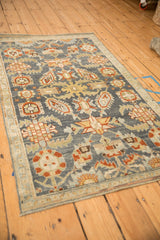 Angled view of a distressed Malayer rug's artistic pattern with interconnected floral buds and serrated leaves.