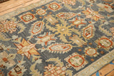 Close-up of expressive serrated leaves and floral buds on a distressed hand-knotted Malayer rug.