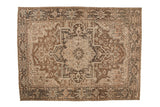 Vintage distressed Heriz carpet with a geometric medallion and floral vines in brown, charcoal, and silver.