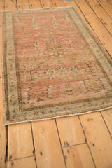 Angled view of a vintage Sarouk rug's allover floral design and abrashed dusty blush field.