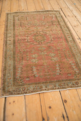 Angled view of a vintage Sarouk rug showing its abrashed dusty blush field and floral motifs.