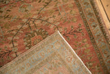 Corner of a distressed Sarouk rug folded to reveal its hand-knotted construction and floral pile texture.