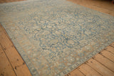 Perspective view of a distressed Tabriz carpet's corner showing the low pile and sand-colored lotus flower border.