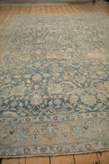 Low angle view across the distressed floral field and lotus motif border of a vintage Tabriz.