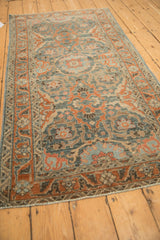 Angled view of a vintage Malayer runner showing its scrolling vine pattern and decorative wear.