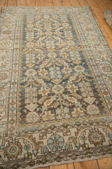 Angled view of a vintage Hamadan rug showing the abrashes in its dusty teal Herati design.