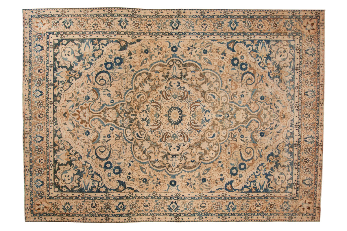 Distressed Bakhtiari carpet with a concentric medallion and scrolled florals in sapphire blue, sand, and ivory.