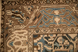 Corner spandrel detail on a distressed Bakhtiari carpet with brown and blue floral vine borders.