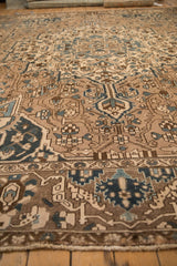 Angled view of a distressed Bakhtiari carpet, with a low pile in coffee brown and dusty blue hues.