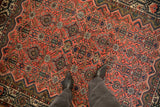 Floral bouquets and interconnecting vines on the brick red field of a vintage Persian Malayer rug.