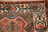 Corner detail of a vintage Malayer rug highlighting the ivory cartouche border and brick red field.