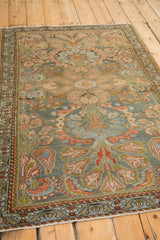 Angled view of a vintage Mehreban rug showcasing its distressed pile and blush boteh paisley design.