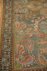 Close view of the meandering vine border and boteh motifs on a distressed Persian rug.