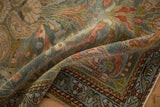 Softly folded corner of a vintage Mehreban rug showing its low pile and detailed floral border.