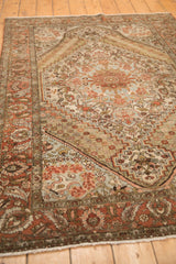 Low perspective across a distressed Bakhtiari rug showing layered floral patterns and a stepped medallion.
