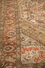 Low-pile texture on a distressed Persian rug showing its brick red paisley border and ivory field.