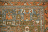 Corner view of the distressed rug's terracotta serrated leaf border and geometric blue field.