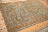 Angled view of the vintage distressed Mehreban rug's geometric Herati field and main border.