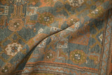 Folded view revealing the distressed texture and geometric Herati border of a vintage rug.