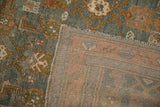Corner of a distressed Persian rug, revealing the hand-knotted back and low, textured pile.