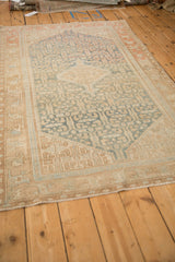 Angled view of the vintage Malayer rug's distressed texture and geometric sky blue design.