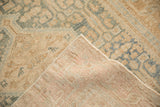 Folded corner of a vintage Malayer rug revealing its hand-knotted foundation and side selvage.