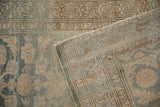 Folded corner of a distressed Persian Malayer rug reveals its hand-knotted foundation and low pile.