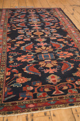 Angled view of the vintage Mehreban rug's palmettes and serrated leaves on a navy blue field.