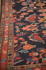 Angled view highlighting the deep navy pile and intricate floral arabesque motifs of a vintage Mehreban rug.