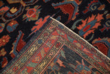 Corner of a vintage Mehreban rug folded to show the hand-knotted foundation and serpent design border.