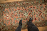 A standing view showing the distressed texture and blush field of a vintage Lilihan rug runner.