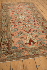 Angled perspective of a distressed Persian runner with blush, pomegranate red, and slate blue floral patterns.