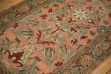 A vintage Lilihan rug's floral clusters and slate blue border over a soft blush field.
