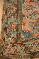 Detail of a vintage Lilihan rug's floral clusters and interconnecting vine border in slate blue and blush.