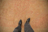 Vintage distressed Oushak carpet texture with softened dusty blush and pale gold floral motifs.
