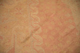 Distressed Oushak carpet pile showing worn rose and pale gold lattice floral patterns.