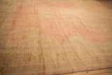 Distressed Oushak carpet detail, showing muted rose and pale gold tones with simplistic floral patterns and worn texture.