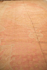 Distressed vintage Oushak carpet pile featuring soft rose, blush, and pale gold motifs.