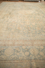 Low-angle view of a distressed Kashan carpet highlighting its even wear and soft seafoam green pattern.