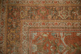 Worn corner of a distressed Mahal carpet with floral borders in madder red, silver, and pale blue.