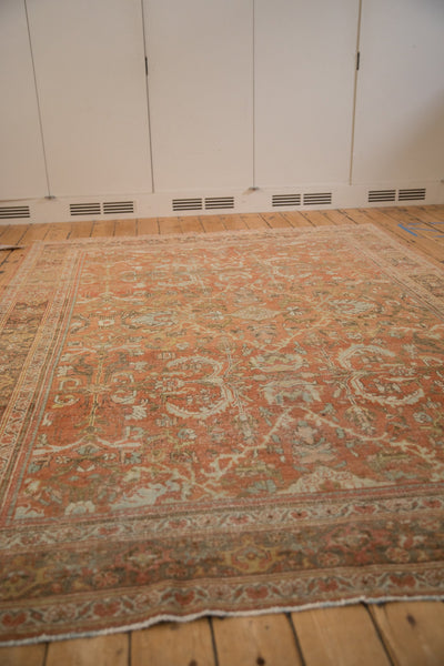 Vintage distressed Mahal carpet with a sprawling floral pattern shown from an angled perspective.