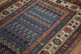 Antique Caucasian rug showing crab border, sapphire blue field, and germinating plant motifs.