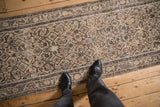 Beige and charcoal Herati pattern on a distressed Hamadan runner with time-softened border.